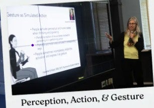 Woman with microphone presenting to a group points to a slide about gestures