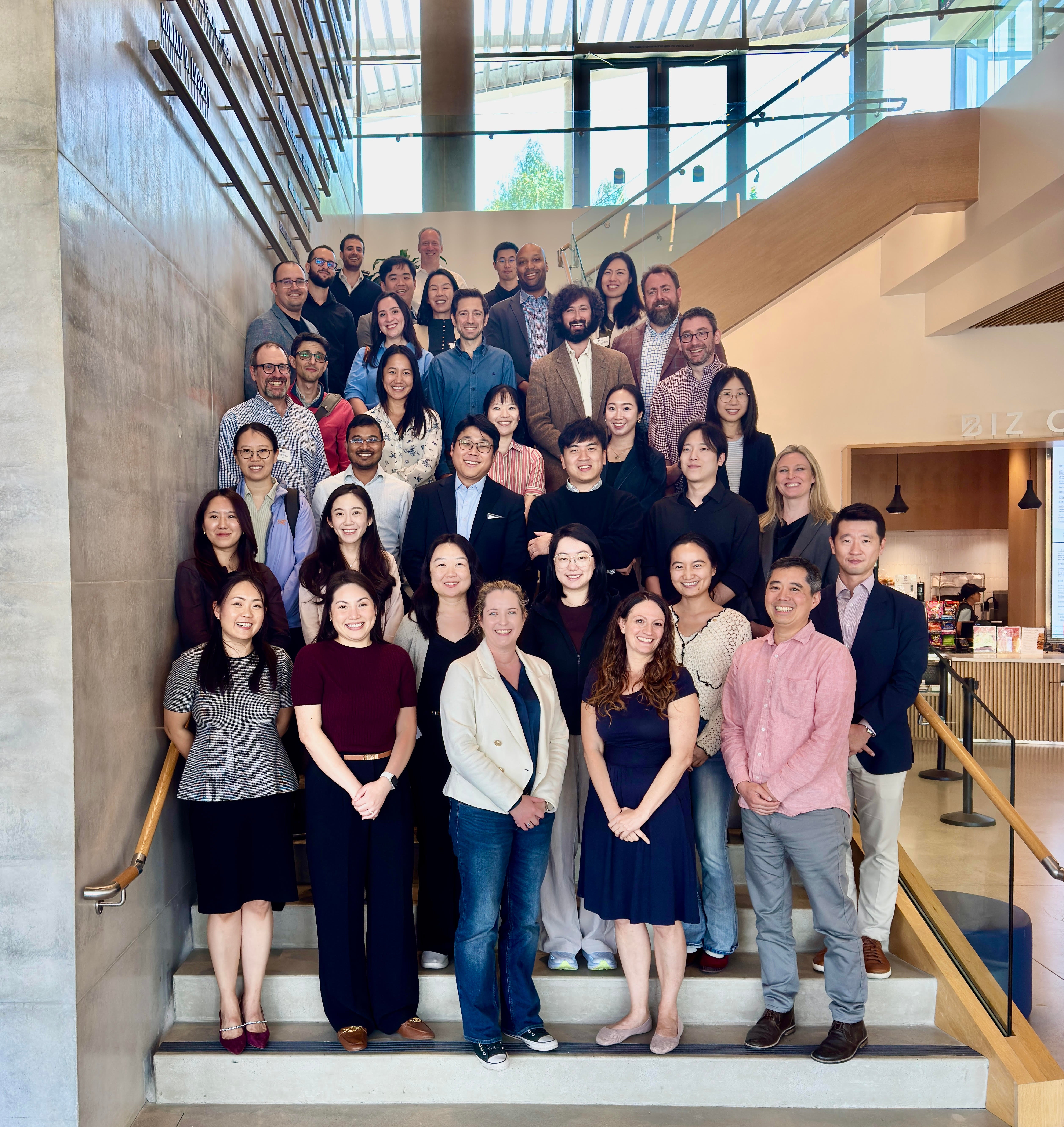 A group of business students and faculty stand on the steps of the new School of Business building