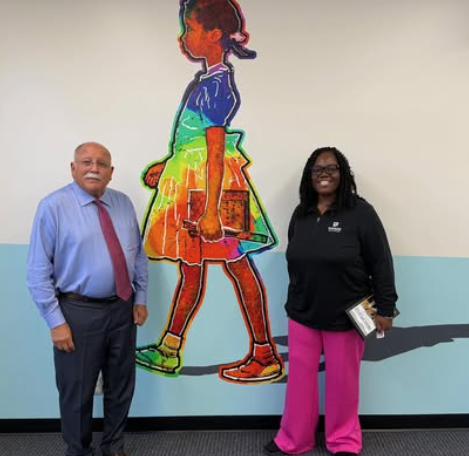 Two people standing on either side of a mural depicting Ruby Bridges
