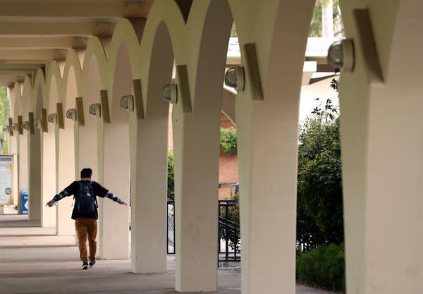 Person walking through Rivera Library arches with arms out